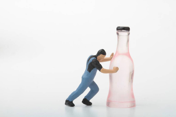 miniature figurine of a man pushing an alcoholic drink bottle  - Fotó, kép