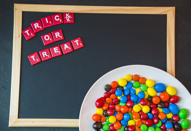 Truc of behandelen word op blackboard met kleurrijke chocolade candy1 - Foto, afbeelding
