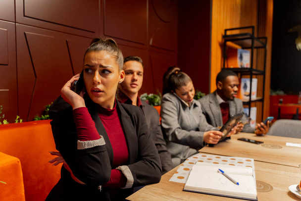Grupa wielorasowych biznesmenów rozmawia przez telefon siedząc - Zdjęcie, obraz