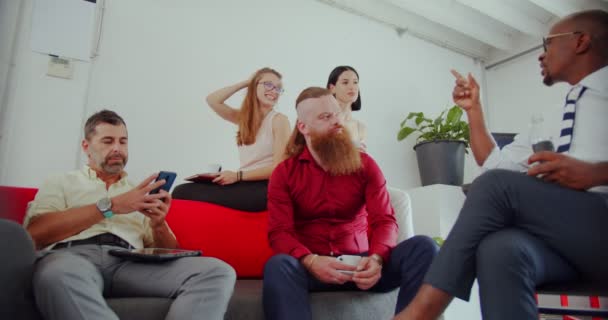 Група багаторасових співробітників розмовляють про свою каву під час сидіння на дивані
 - Кадри, відео