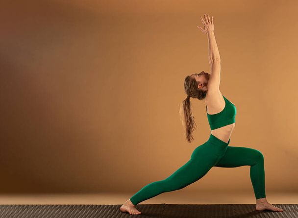 Aantrekkelijk en mooi jong meisje doet een yoga pose - Foto, afbeelding