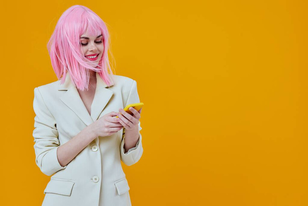 alegre glamorosa mujer rosa peluca hablando por teléfono amarillo fondo - Foto, Imagen