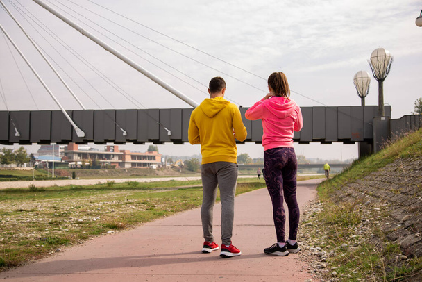 Удивительная и привлекательная сильная пара стоит на беговой дорожке во время разговора - Фото, изображение