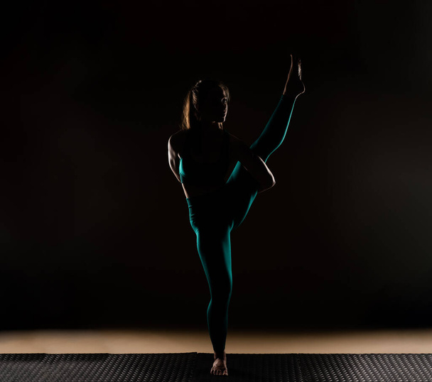 Silhouette vonzó és gyönyörű lány egyensúlyozik az egyik lábán - Fotó, kép