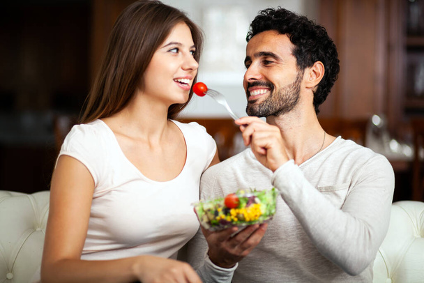 Couple eating a salad in the living room. - Foto, Imagen