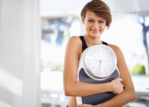 Good news from her scale today. A beautiful young woman standing holding a scale. - Foto, Imagen