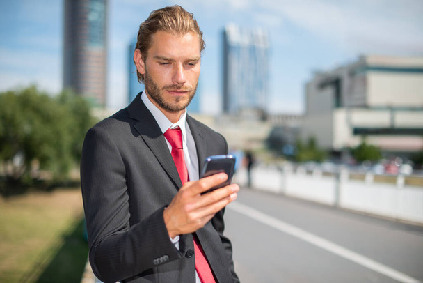 Businessman using his cellphone on a city road - Photo, Image