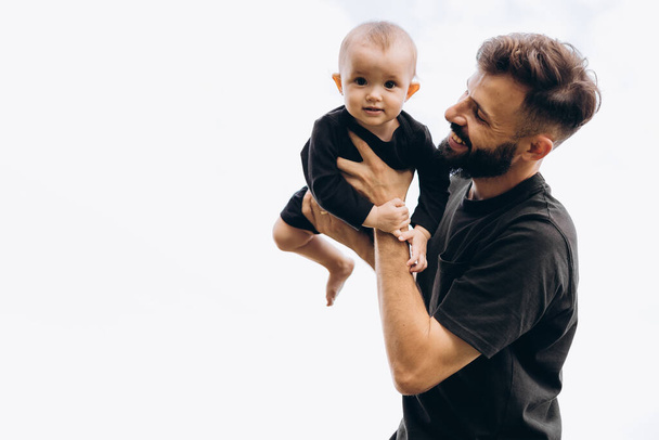 portrait of father and child. A stylish father with a beard keeps on his arms a child, a little girl, they embrace and smile, rejoice and have fun. Happy Father's Day - Foto, Bild