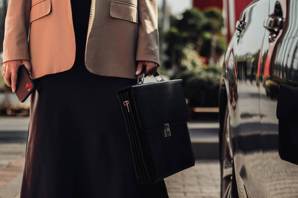Tuntematon tyylikäs liike nainen salkku ja älypuhelin seisoo lähellä Luxury Car - Valokuva, kuva
