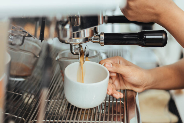 Barista robi kawę z ekspresem do kawy w kawiarni. Zamknij ręce barista do robienia espresso strzał z maszyny. Koncepcja właściciela kawy. - Zdjęcie, obraz