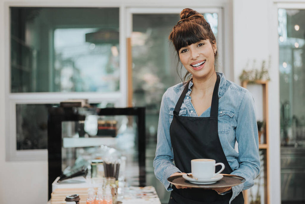 Caucasian woman barista holding cup of coffee. female barista working in coffee shop. Coffee owner concept. - Photo, Image