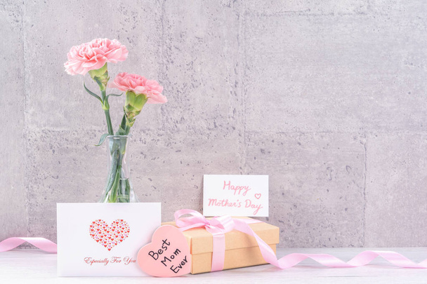 Mothers day handmade giftbox surprise wishes photography - Beautiful blooming carnations with pink ribbon box isolated on gray wallpaper design, close up, copy space - Foto, Bild