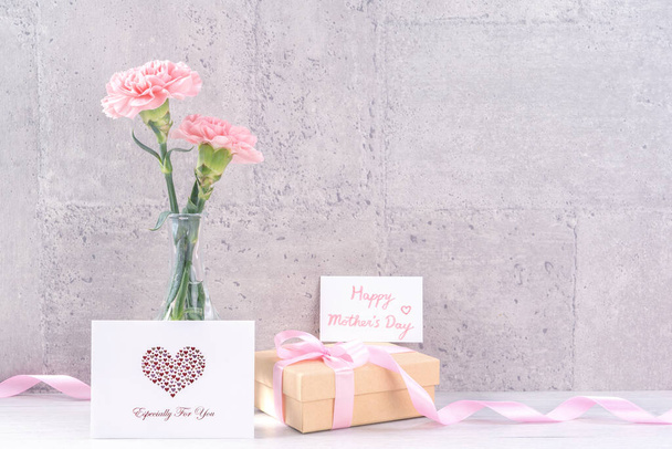 Mothers day handmade giftbox surprise wishes photography - Beautiful blooming carnations with pink ribbon box isolated on gray wallpaper design, close up, copy space, mock up - Фото, зображення
