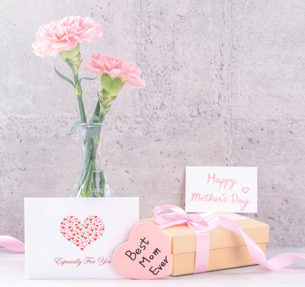 Mothers day handmade giftbox surprise wishes photography - Beautiful blooming carnations with pink ribbon box isolated on gray wallpaper design, close up, copy space - Zdjęcie, obraz