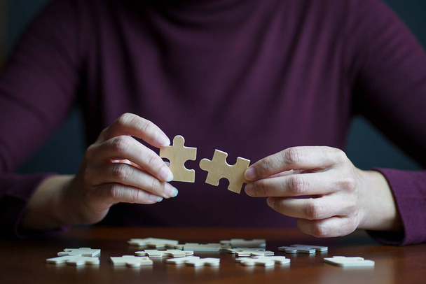 Clsoe up view of woman connecting jigsaw puzzle. Team work, success or strategy concept. - Foto, Imagem