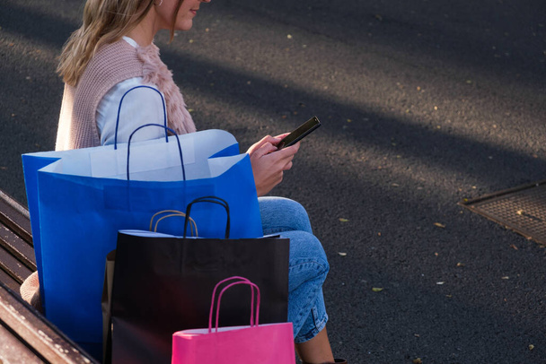 Nuori nainen käyttää älypuhelinta ostosten jälkeen - Valokuva, kuva
