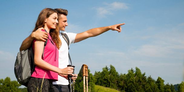 active Beautiful young couple hiking ina nature climbing hill or mountain - man and woman trekking - Фото, изображение