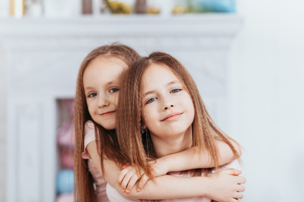 Zwei hübsche kleine Mädchen kuscheln und lachen fröhlich - Foto, Bild
