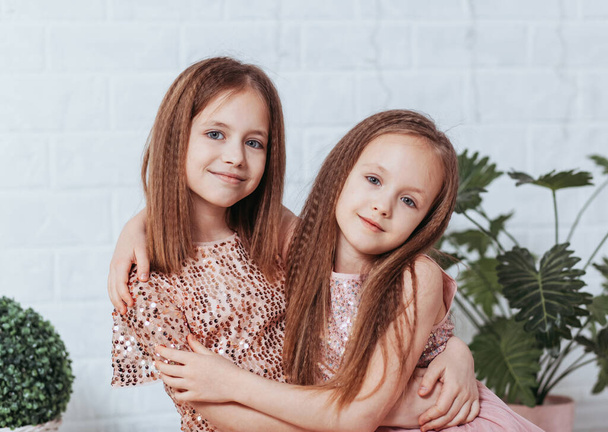Two pretty little girls sisters happily cuddle and laugh - Photo, Image