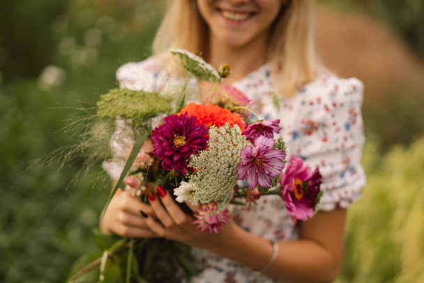 Ein Teenager-Mädchen spaziert mit einem Blumenstrauß in einer floristischen Blumenfarm. - Foto, Bild