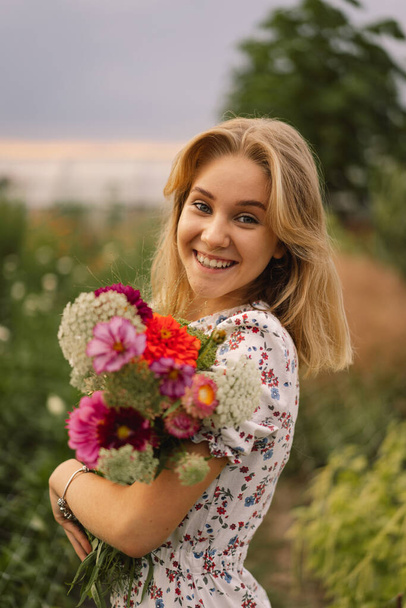 A teenage girl walks with a bouquet of flowers in a floristic flower farm. - Fotoğraf, Görsel