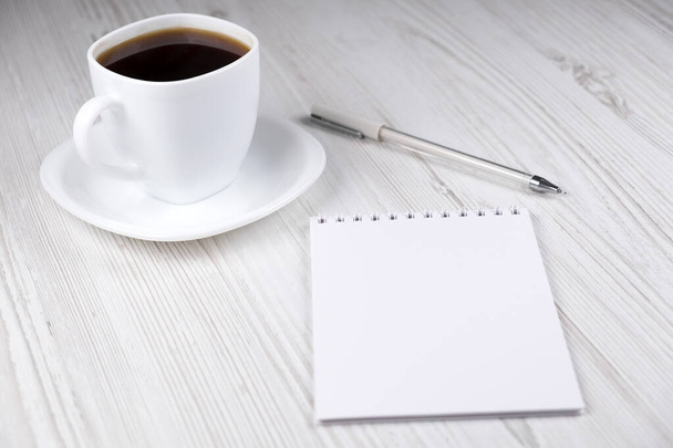 Чашка кави, блокнот і біла ручка на дерев'яному столі. Офіс
 - Фото, зображення