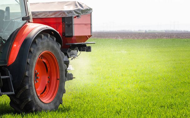 Tractor propagando fertilizantes artificiales. Transportes, agricultura. - Foto, Imagen
