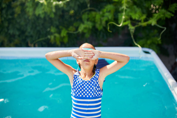 Gözlüklü mutlu küçük kız eğleniyor, yüzme havuzunda yüzüyor, yaz tatilinde evde, tropik tatil beldesinde. - Fotoğraf, Görsel