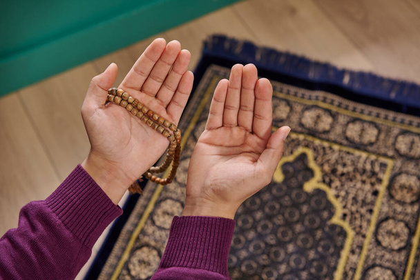 Мусульманин молится, сидя на молитвенном ковре в доме концепции, интерьер, рамадан, четки, закрыть руку, ислам, Рамадан, пятница. - Фото, изображение