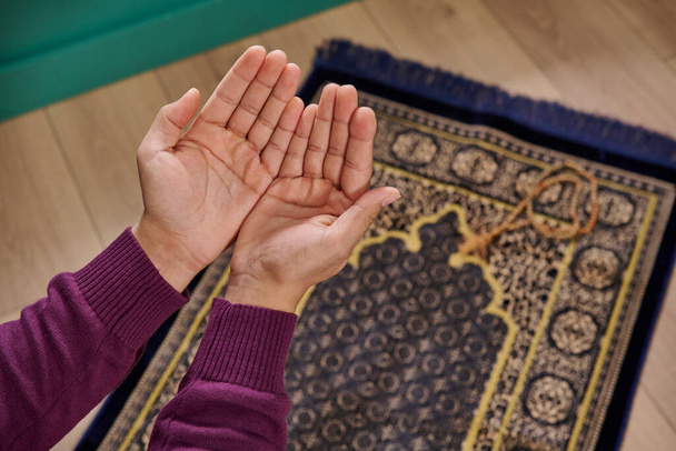 Muslim muž se modlí, sedí na modlitebním koberci v domácím konceptu, interiér, ramadán, růženec, zblízka otevřenou ruku, islám, ramadán, pátek. - Fotografie, Obrázek