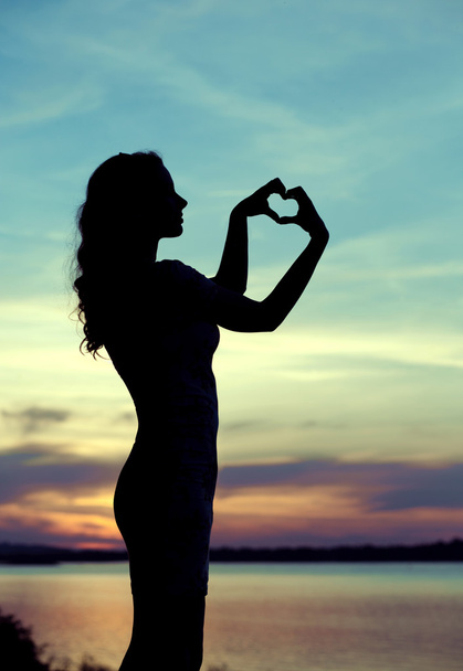 Silhouette of the woman making the heart sign - Фото, изображение