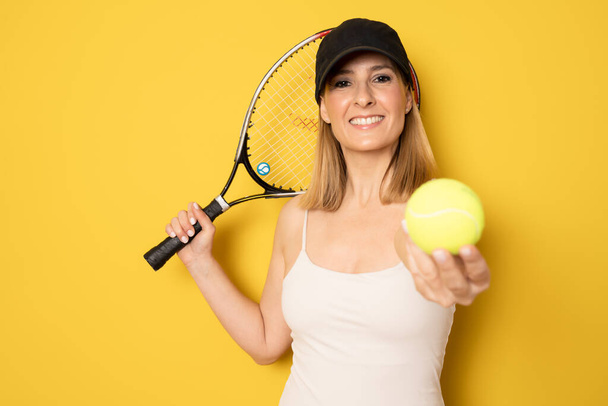 Επιτυχημένη αθλήτρια με ρακέτα στο γήπεδο του τένις. Υγιεινός τρόπος ζωής Απομονωμένα σε κίτρινο φόντο - Φωτογραφία, εικόνα