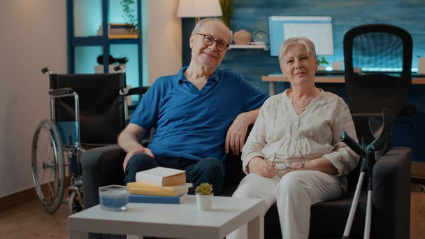 Portrait de couple retraité avec handicap assis sur le canapé - Photo, image
