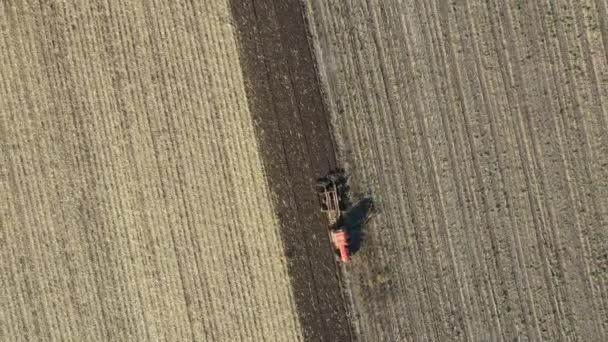 Felül felülnézet, babakocsi mozog lövés traktor, mint húzógép, szívszaggató szántóföld, előkészíti a talaj ültetés új termés a következő szezonban. - Felvétel, videó