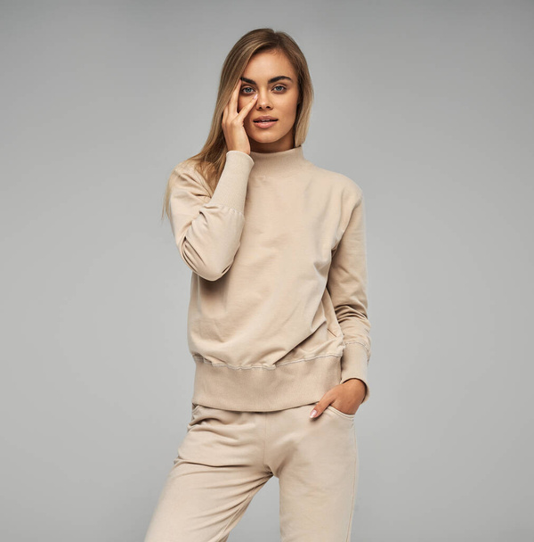 Blonde woman wear of beige set of tracksuit isolated on grey background - Photo, Image