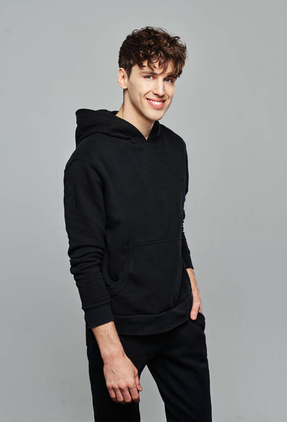 Handsome man wear black set of track suit isolated on gray background - 写真・画像