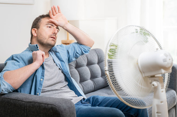 Un homme souffrant de chaleur estivale à la maison essayant de se rafraîchir - Photo, image