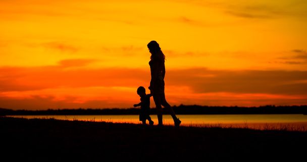 Мать с ребенком смотрят на красивый закат
 - Фото, изображение