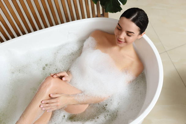 Beautiful young woman taking bubble bath at home - Foto, Imagen