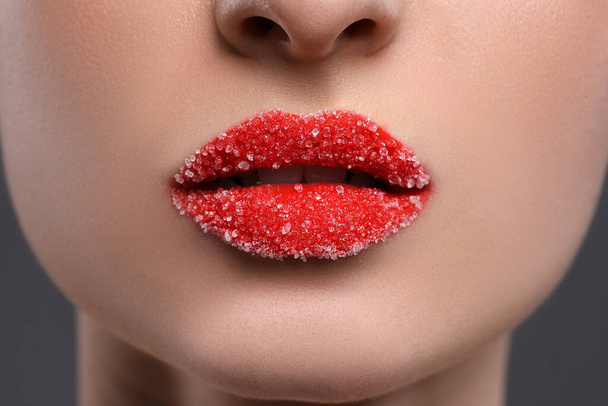 Frau mit schönen Lippen, bedeckt mit Zucker auf grauem Hintergrund, Nahaufnahme - Foto, Bild