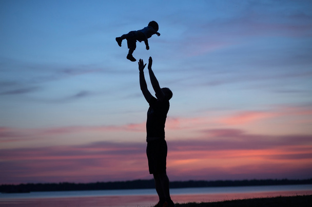 Silhouettes of father tossing his child - Photo, Image