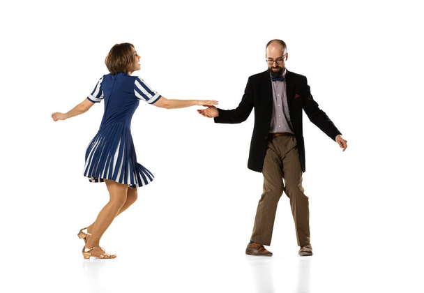 Social dancing. Couple of dancers, young man and woman in vintage retro style outfits dancing swing dance isolated on white background. Timeless traditions - 写真・画像