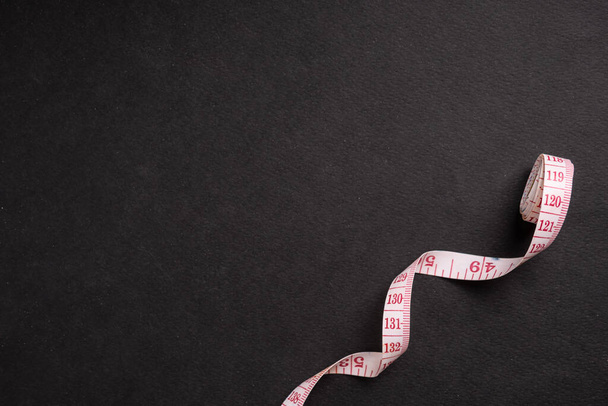 measuring tape on a black background. The concept of weight loss or weight gain. Space for text. - Fotoğraf, Görsel
