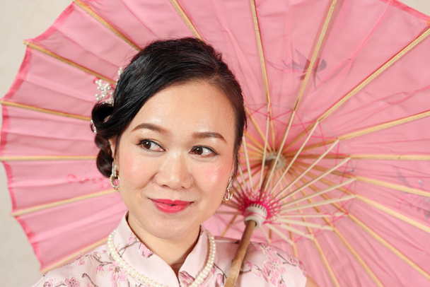 Vonzó középkorú nő visel kínai cheongsam ruha tánc pózol színes papír esernyő - Fotó, kép