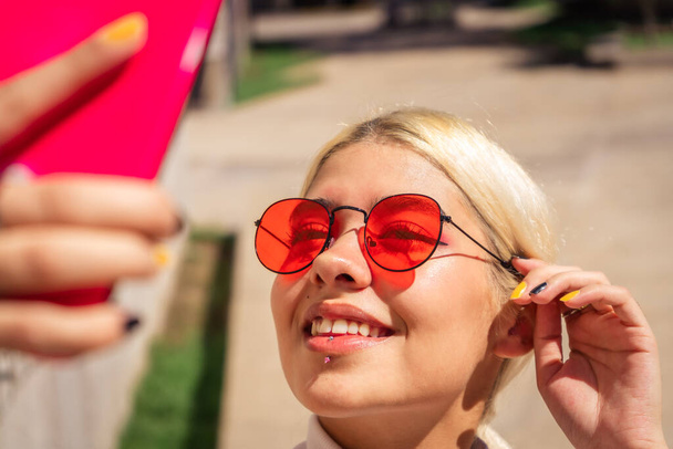 Immagine di una giovane donna latina bella e moderna che si fa un selfie sorridente con il cellulare in un luogo pubblico. Concetti di tecnologia, gioia - Foto, immagini