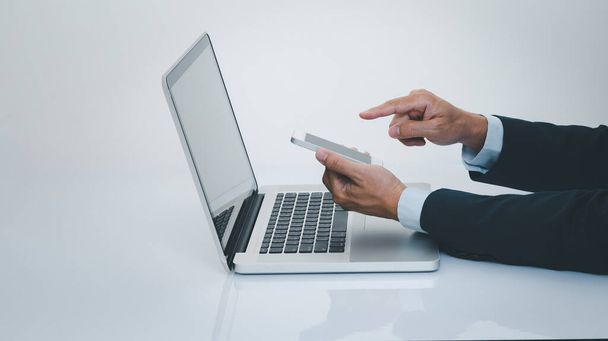 Businessman hand using smartphone with laptop computer. Business and technology concept. - 写真・画像