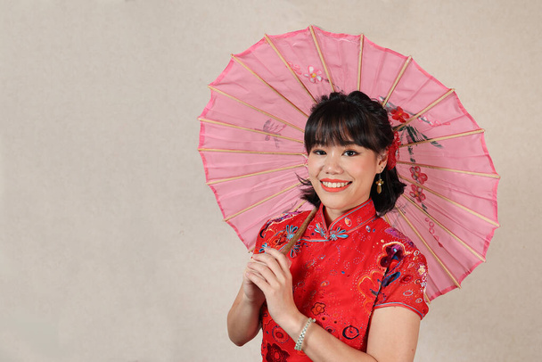 Çekici genç bir kadın eski Çin Cheongsam elbisesi giyiyor. Elinde süslü kağıt şemsiyeyle eski moda poz veriyor. - Fotoğraf, Görsel