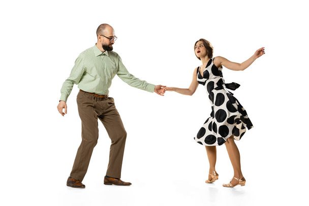 Dynamic portrait of couple of dancers in vintage retro style outfits dancing lindy hop dance isolated on white background. Concept of art, action, motion - Фото, изображение