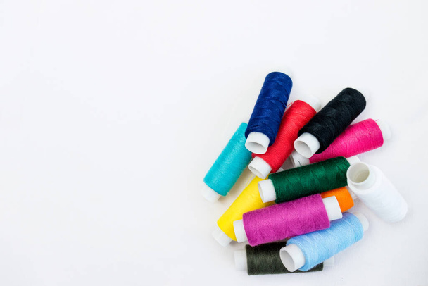 Різнокольорові нитки для шиття на фоні білої бавовняної тканини.селективний фокус
 - Фото, зображення