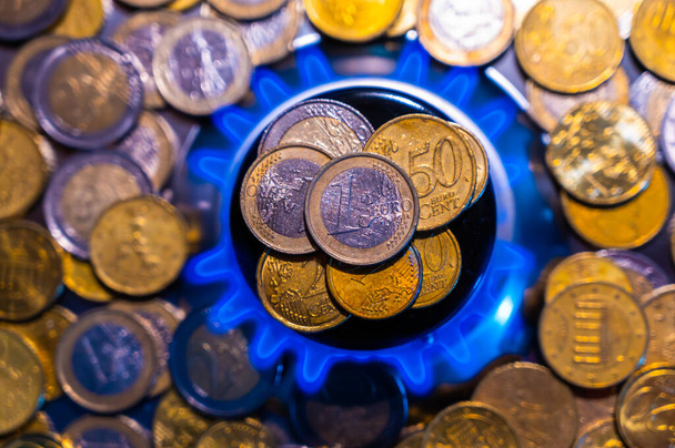 Estufa de gas encendida, con pilas de monedas encima. Aumento de los costes y tarifas del gas. - Foto, Imagen